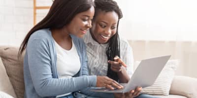Cheerful black women browsing dating website on laptop
