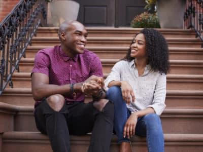 Couple Sit And Talk On Stoop Of Brownstone In New York City