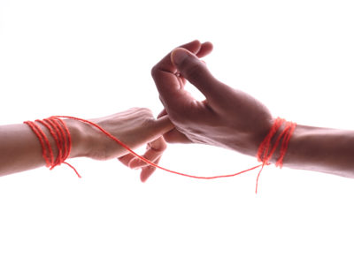 Male and female hands wrapped in red thread isolated on white, concept of desire and love