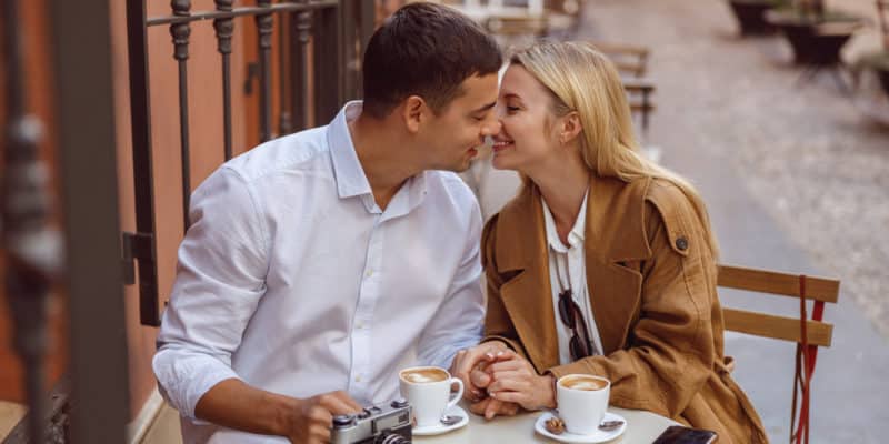 Portrait of lovely couple sitting at table in cafe during date